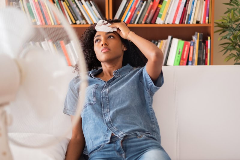 Black woman sweating and trying to refresh at home