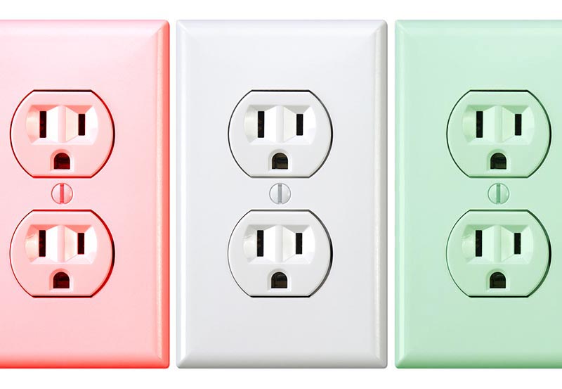Three standard duplex electrical wall outlets displayed side by side in pastel red, white, and pastel green colors.