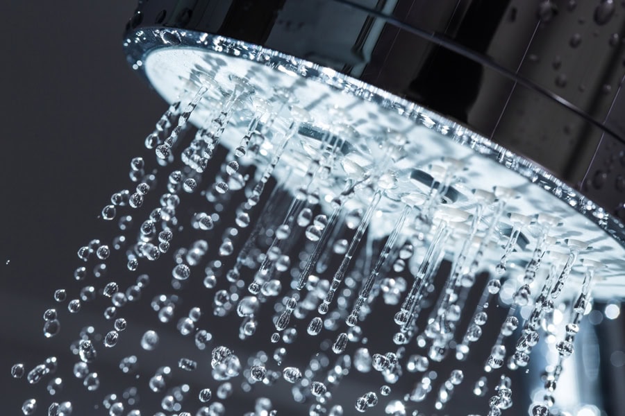 Water coming from a shower head to represent five signs your water heater needs repair services.